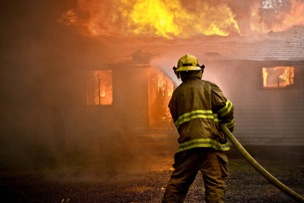 Firefighter spraying water at a house fire